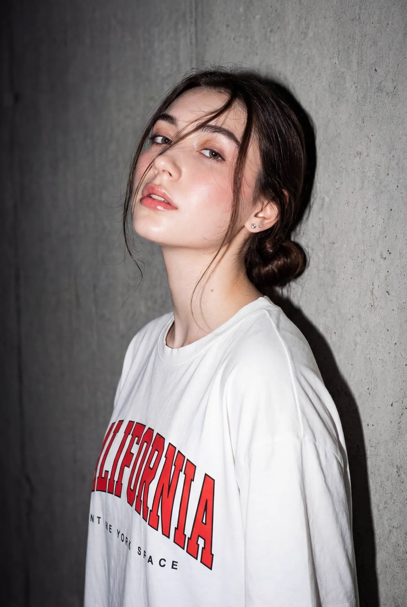 A high-resolution, close-up editorial-style portrait of a young woman standing…