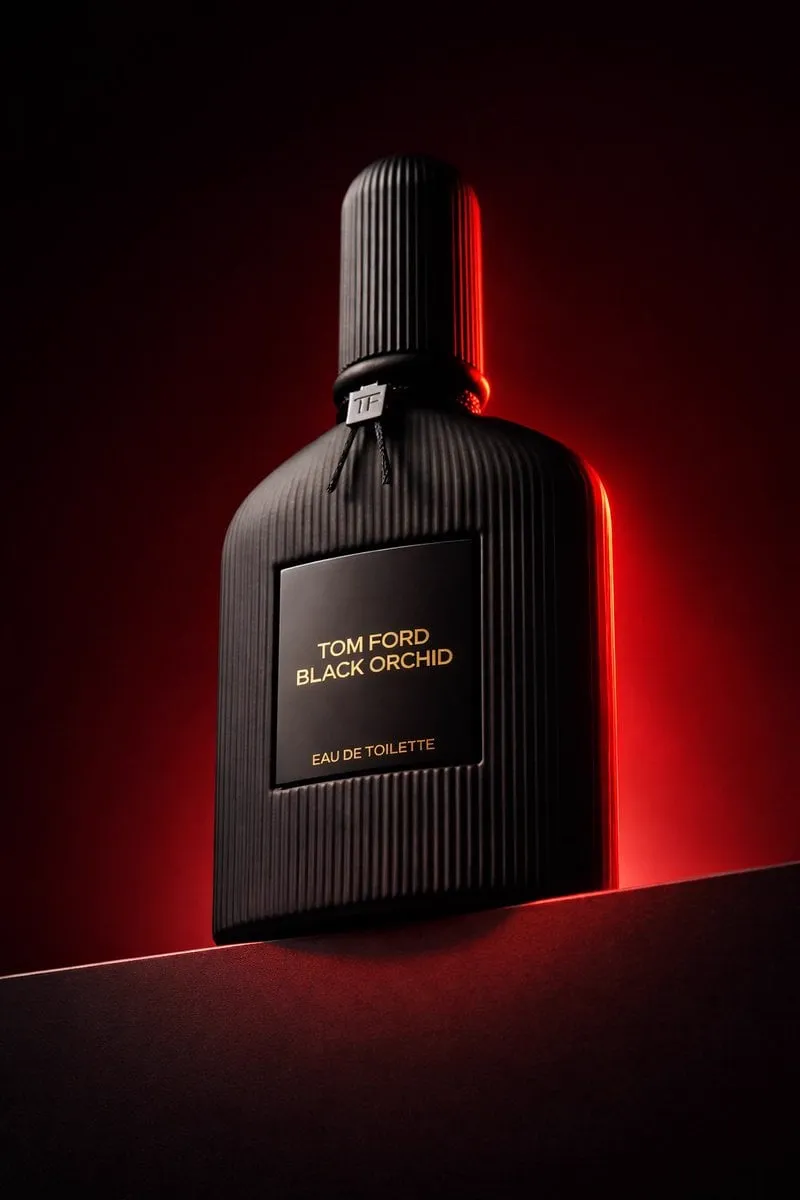 Low angle luxury product photography of a black ribbed glass perfume bottle…