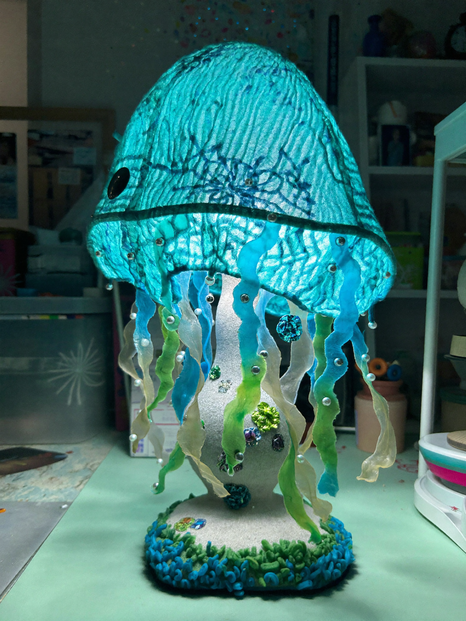 A straight-on medium shot captures a handmade jellyfish-shaped lamp sitting on a...
