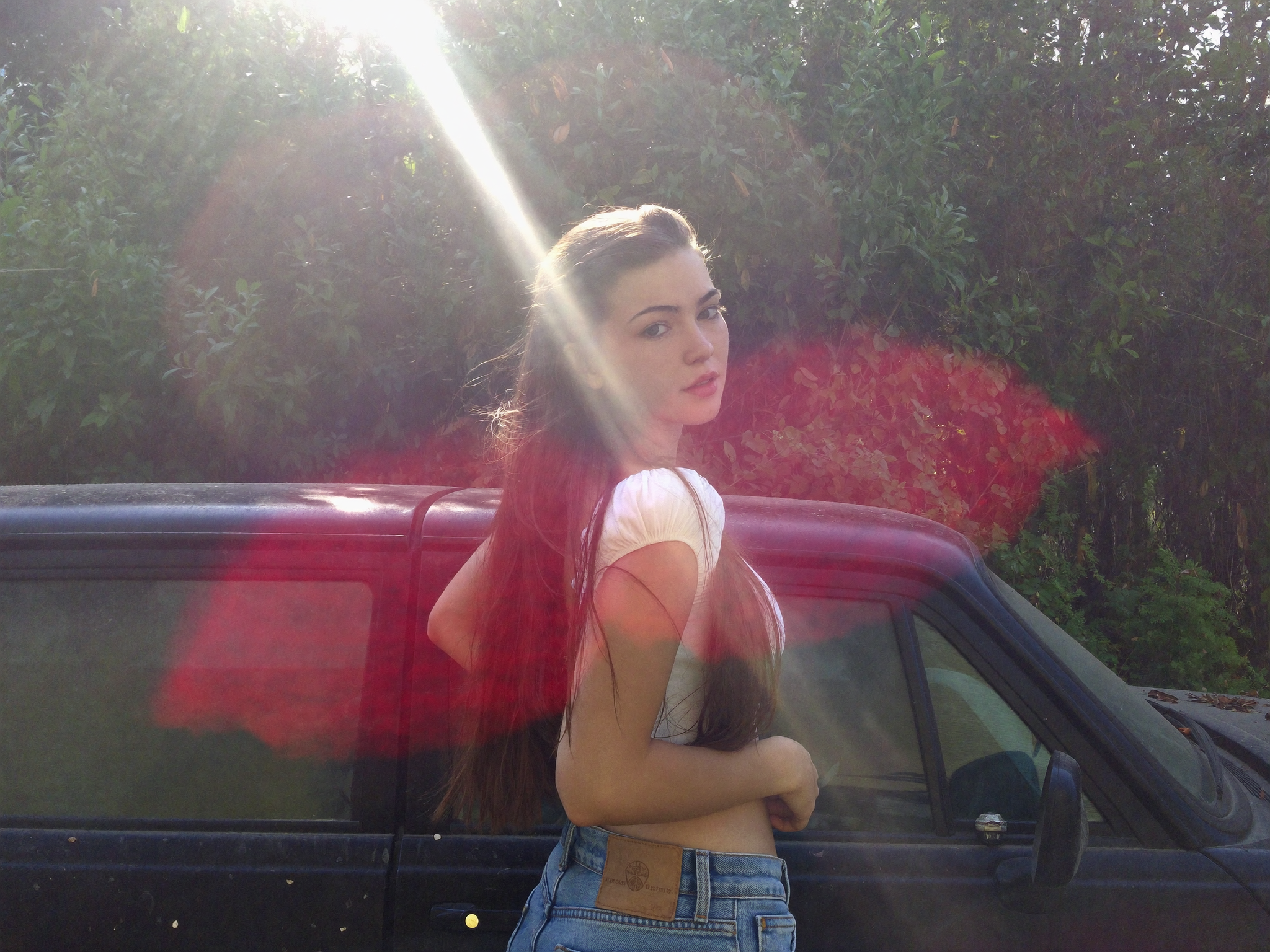 A straight-on medium shot features a young woman with light skin and long brown...