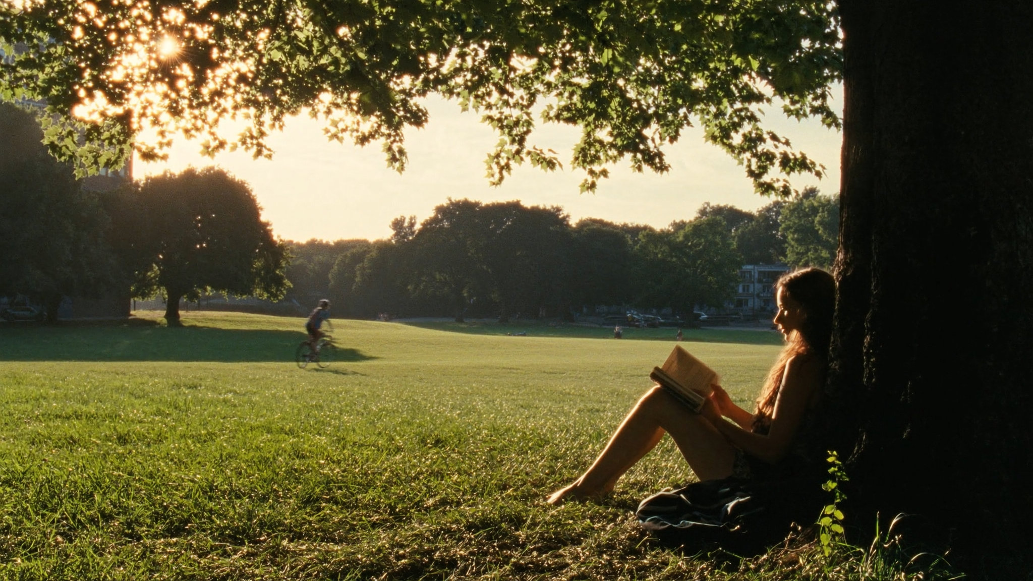 {"Caption": "A late-afternoon slice of quiet: a young woman leans against a tree in...