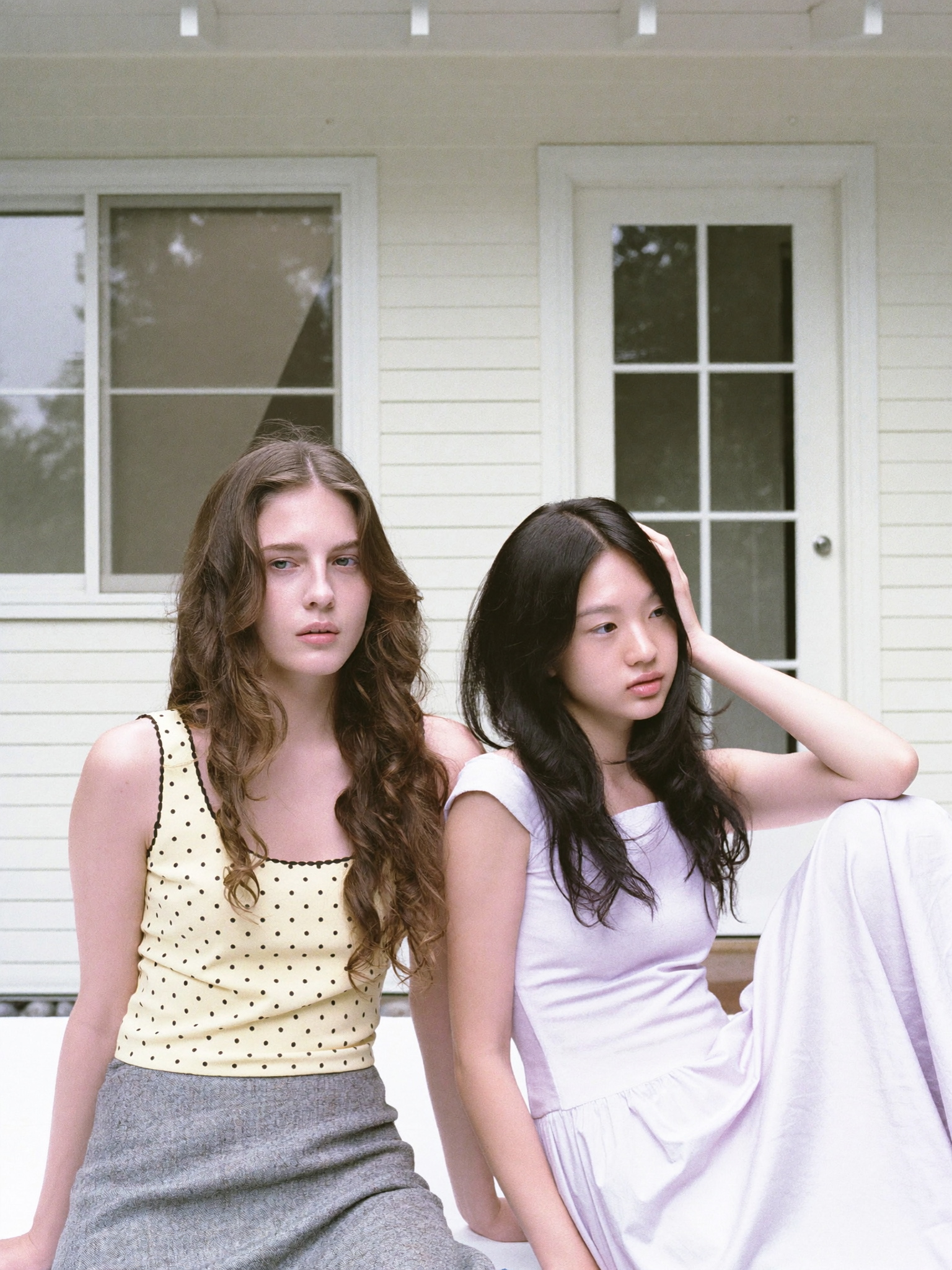A straight-on, eye-level medium shot frames two young women reclining outdoors...