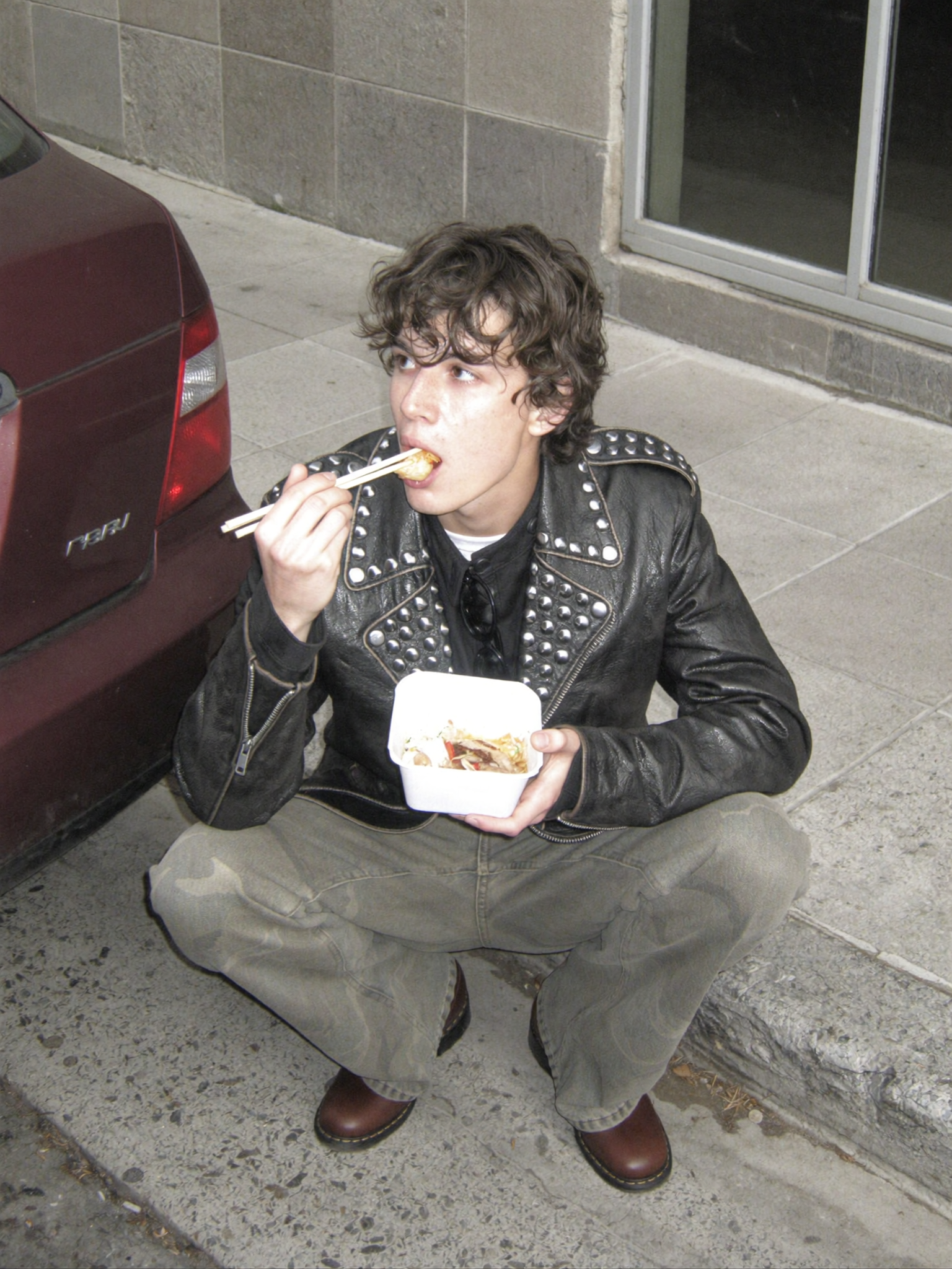 Slightly high-angle medium shot of a young man in his 20s crouching on a concrete...